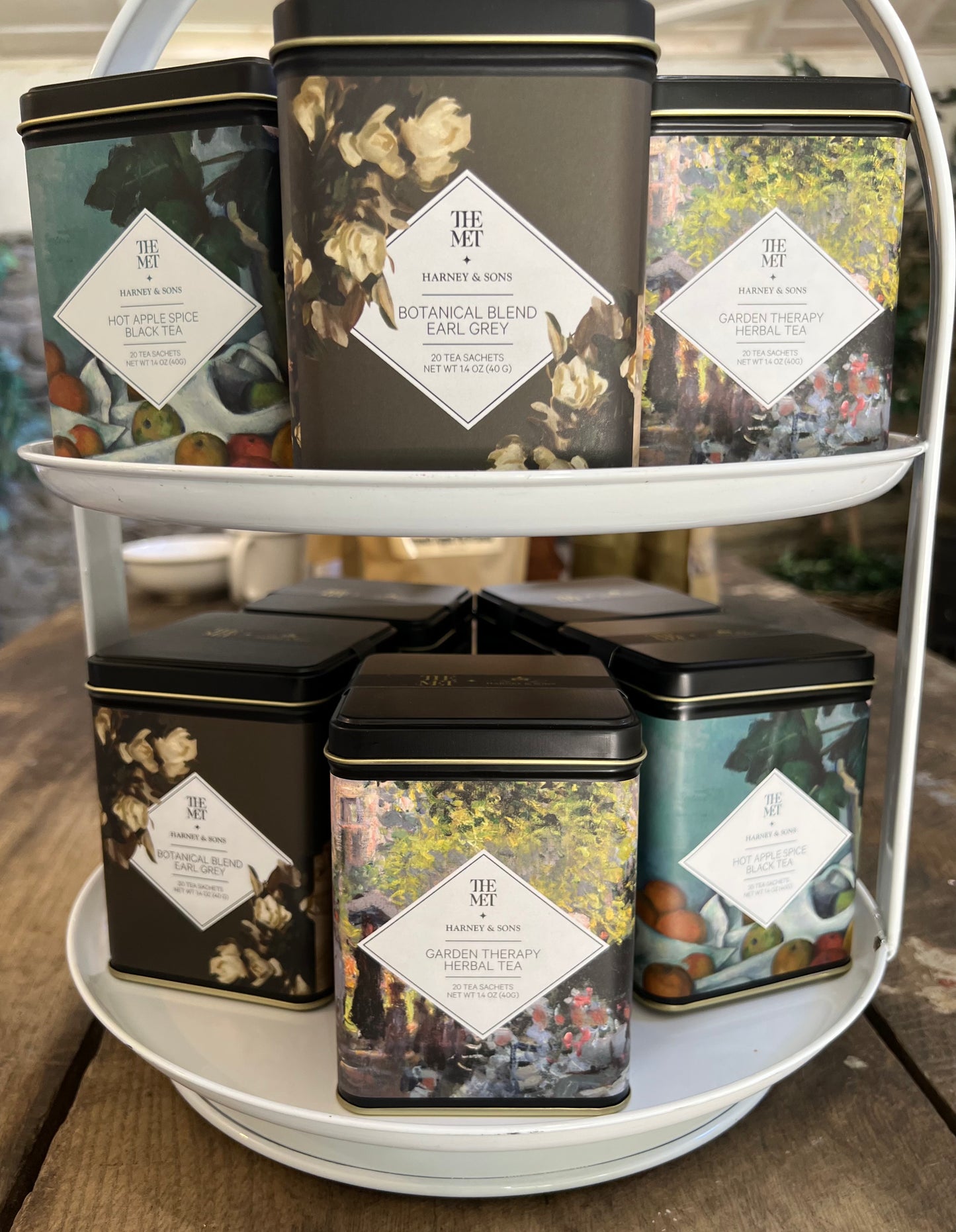 Collection of tea tins on a tiered stand with decorative labels.