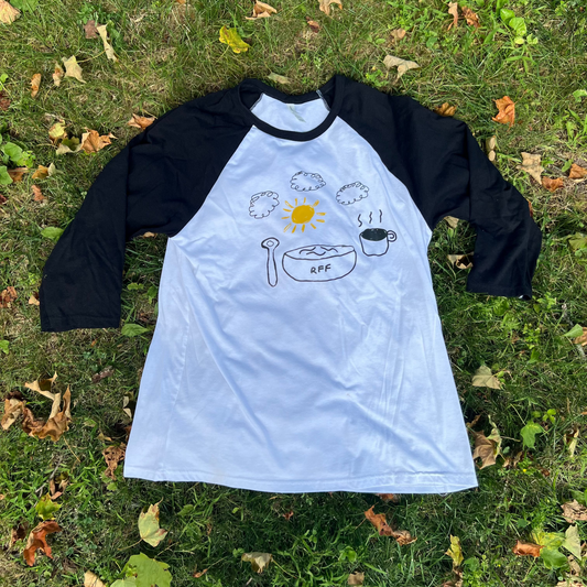 White baseball shirt with black sleeves and graphic design on grass
