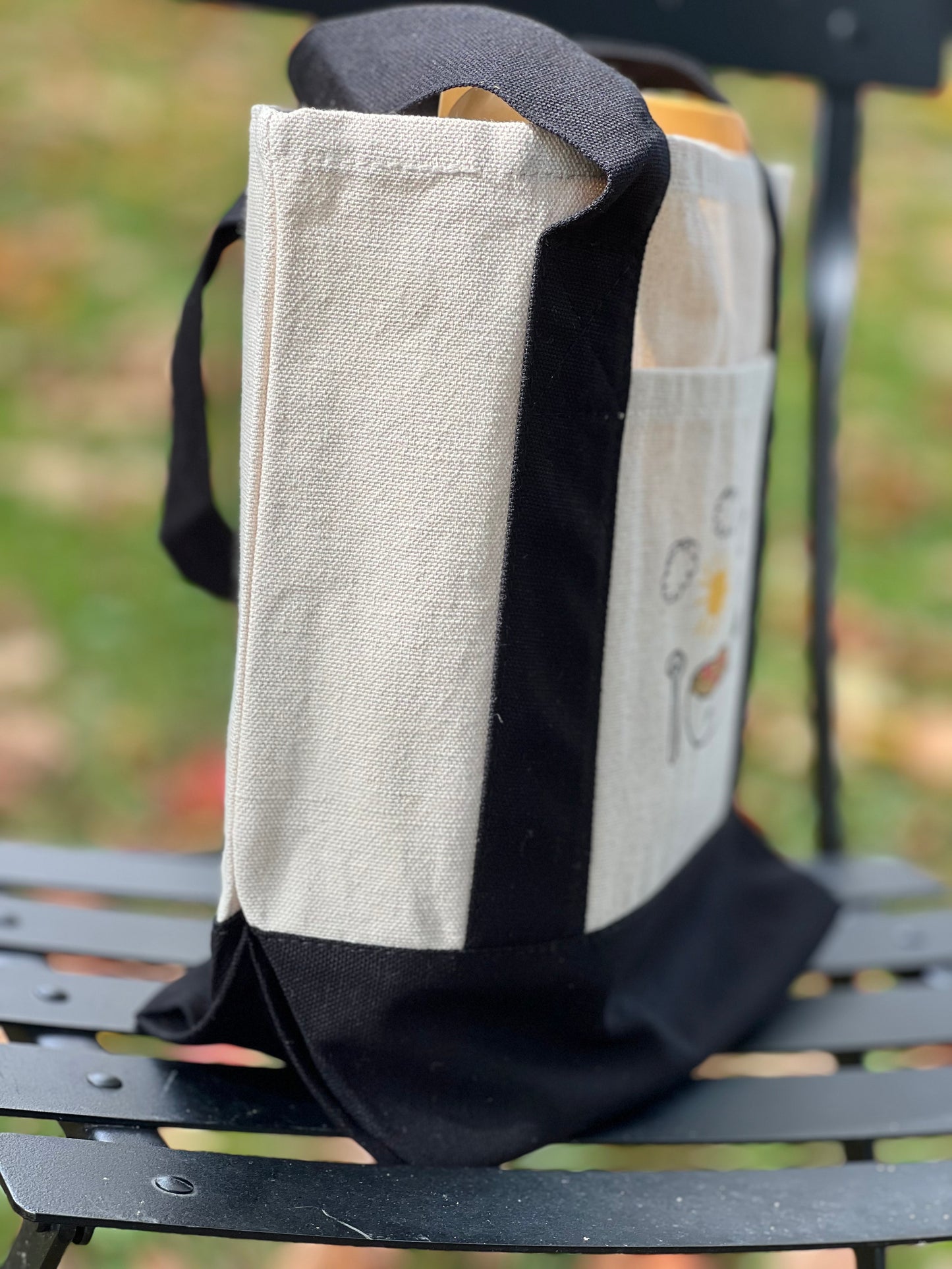 Black and gray bag with a patterned flap on a metal bench