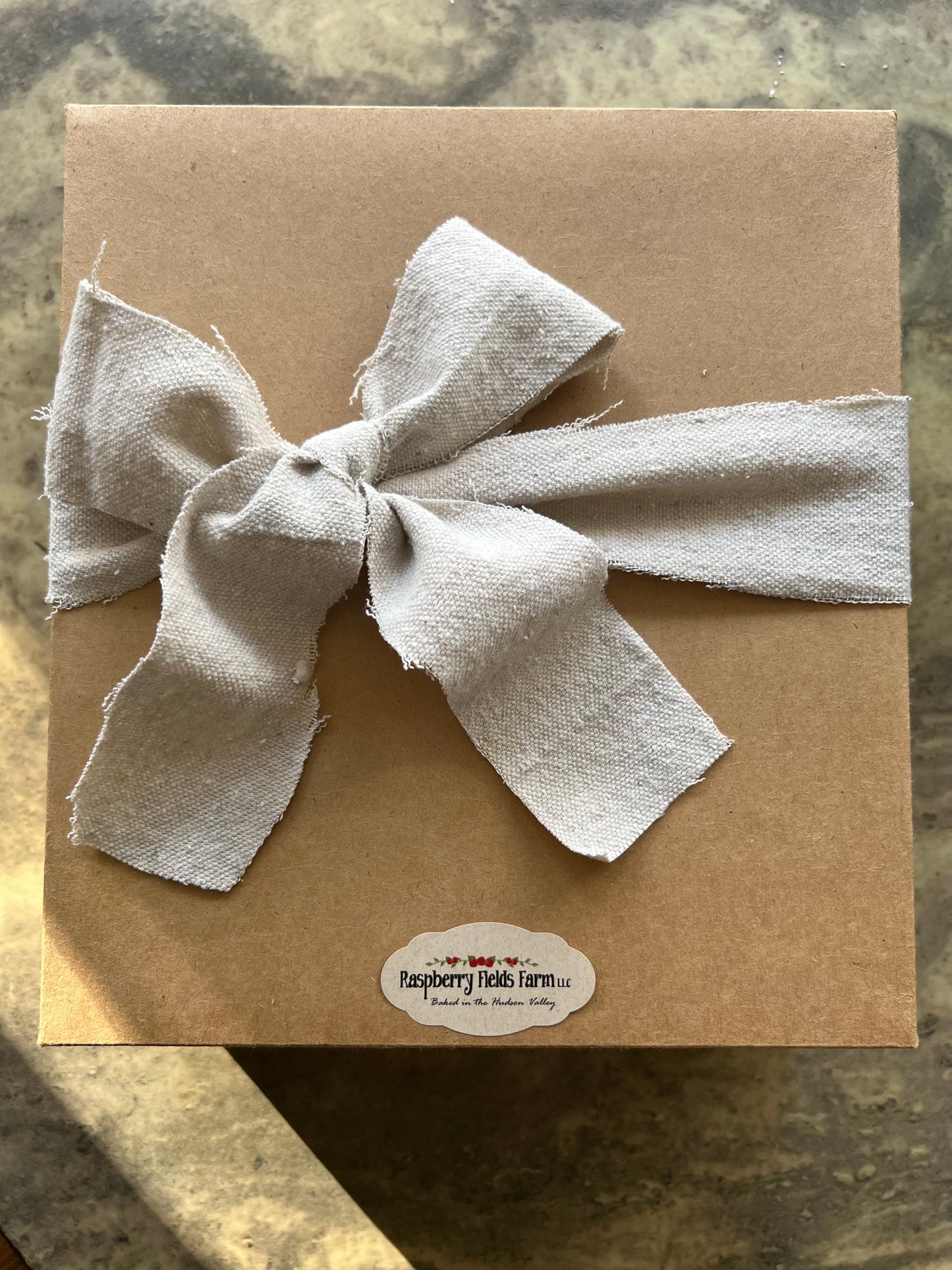 Brown paper package with a large white bow on a textured surface