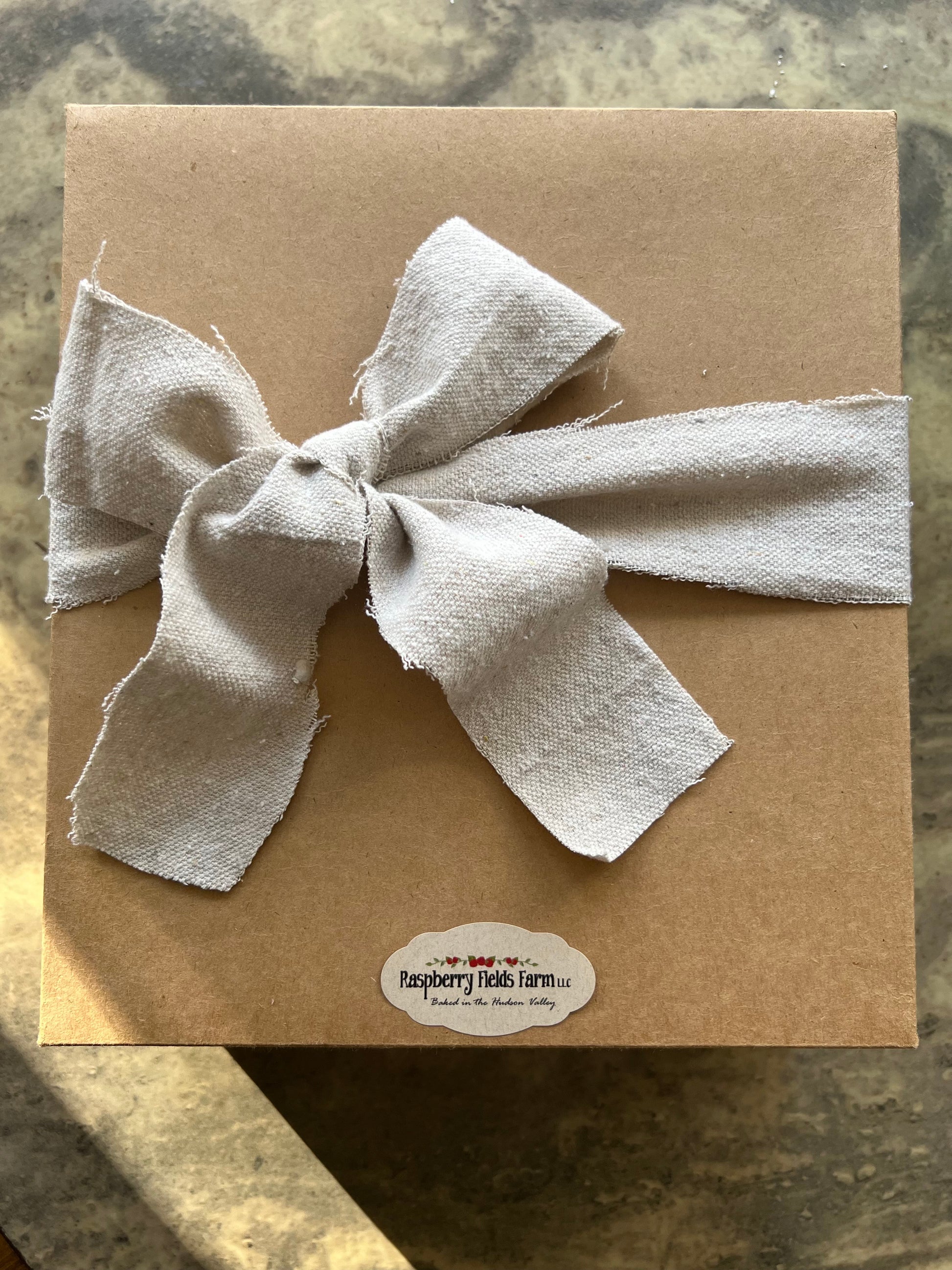 Brown paper package with a large white bow on a textured surface