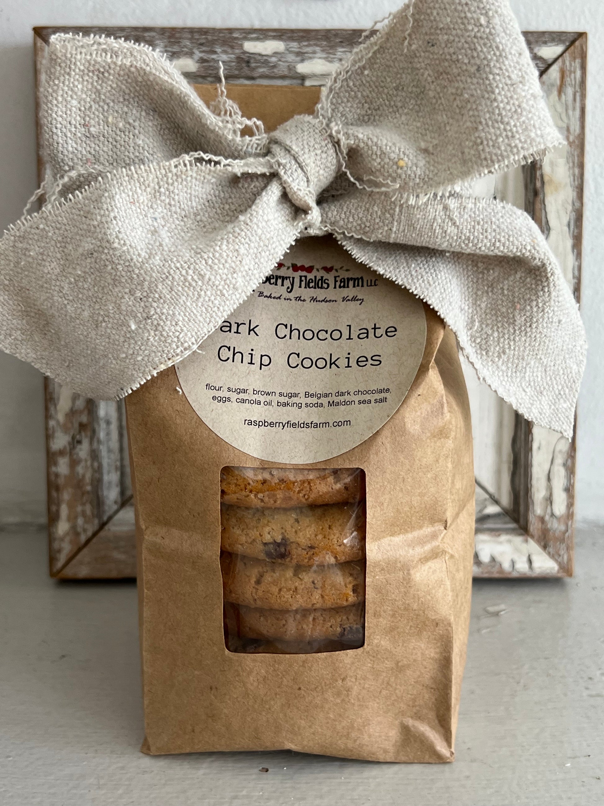 Packaged cookies with a label and burlap ribbon on a rustic wooden surface